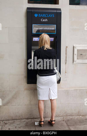 Woman customer using a cash machine at  Barclays Bank ATM automated teller machine in London's St John Wood. DAVID MANSELL Stock Photo