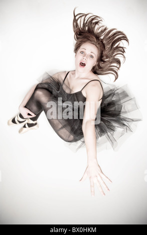 A teenage caucasian ballerina wearing a black tutu jumps in the air. Stock Photo