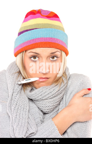 Ill woman wearing a cap and scarf with thermometer in her mouth Stock Photo