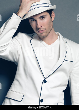 Fashion photo of a young man wearing a white blazer and a hat Stock Photo