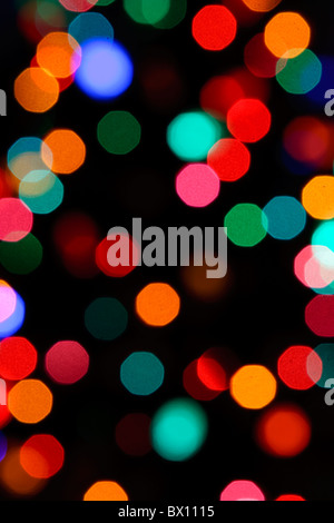 Slightly octagon bokeh circles of out of focus Christmas lights in a dark room. Stock Photo