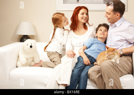 Friendly family members sitting on comfortable sofa and communicating at home Stock Photo