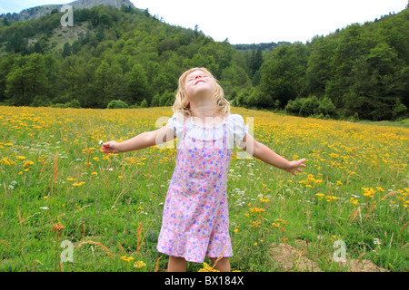 Open arms girl in beautiful flower spring meadow in Pyrenees mountains Spain Stock Photo