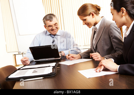 Photo of friendly business group sitting at the desk in the office and planning work Stock Photo