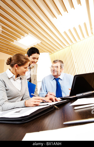 Photo of friendly business group sitting at the desk in the office and planning work Stock Photo
