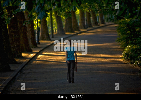 By a late afternoon, a young Lady having a walk in one of the parks of Vichy. Jeune femme se promenant dans un parc de Vichy. Stock Photo