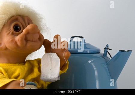 Grandmother troll holding in her hand a teabag with teakettle in background. She is ready to make tea. Copy space. Stock Photo