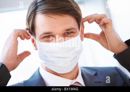 Portrait of businessman with protective mask going to put it on Stock Photo