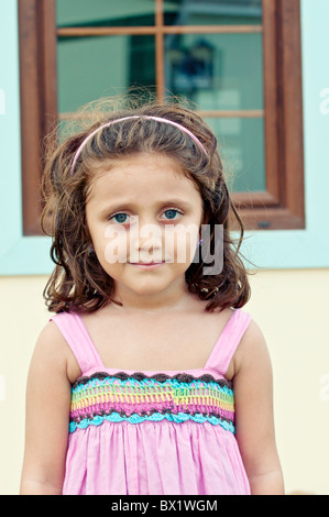 Beautiful little girl standing outside her house in pink dress Stock Photo