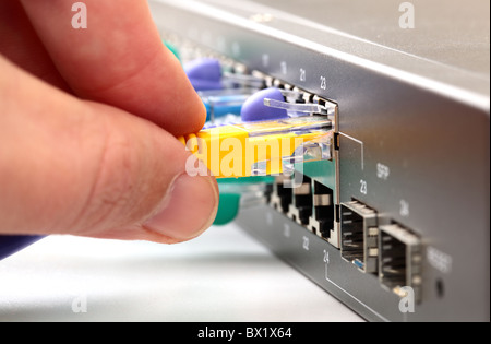 Hand connecting yellow internet cable to hub Stock Photo