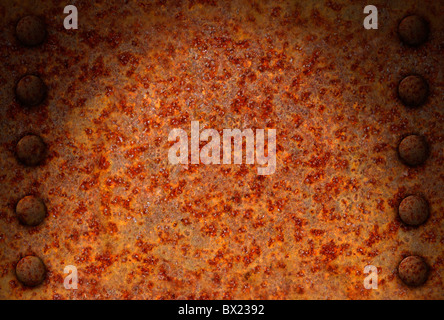 Rusted metal surface with rivet bolts dramatically lit from above Stock Photo