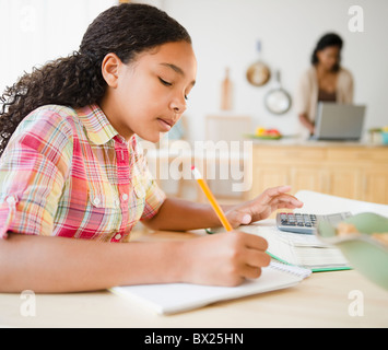 Mixed race girl doing homework in kitchen Stock Photo