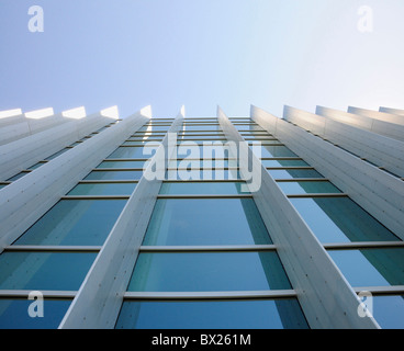 Exterior windows of a commercial office building looking up from the ground with blue sky reflected in windows Stock Photo