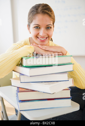 Smiling Indian student leaning on stack of textbooks Stock Photo