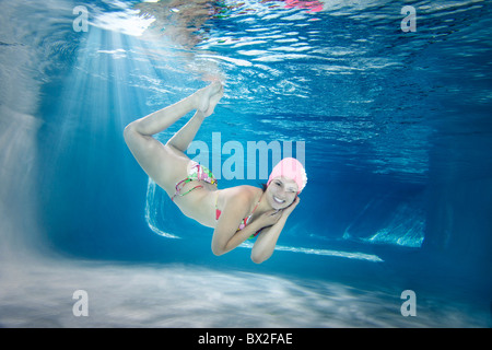 Hispanic woman in bikini swimming underwater Stock Photo