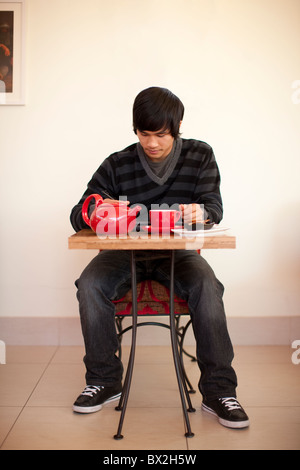 Mixed race man drinking tea and using digital tablet at cafe Stock Photo