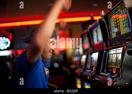 Cheering Native American man playing slot machines in casino Stock Photo