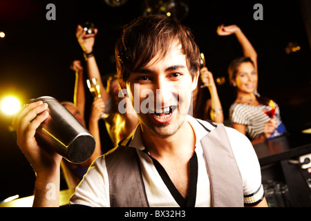 Portrait of smiling male with bottle looking at on background of dancers Stock Photo