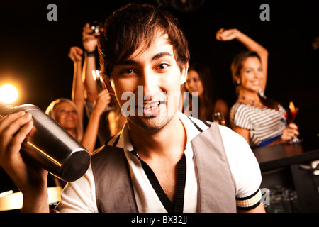 Portrait of smiling male with bottle looking at on background of dancers Stock Photo