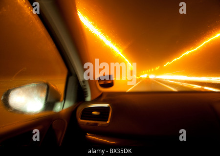 Night Driving - on a UK motorway - with harsh headlights and light trails - a cause of driver tiredness and loss of control. Stock Photo