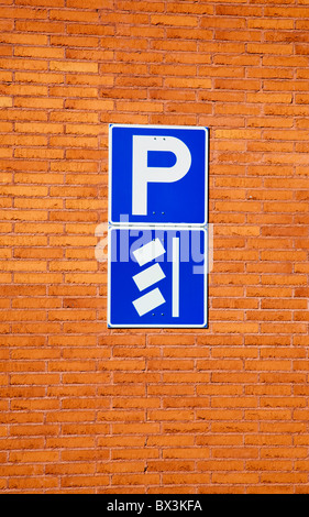 Blue parking lot sign on orange brick wall , Finland Stock Photo