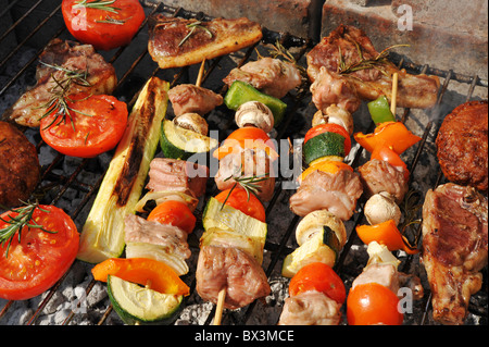 Meat and vegetables cooking on the barbecue outdoors. Centre focus. Stock Photo