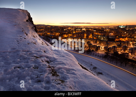 Looking down on Edinburgh at sunset from snow covered Salisbury Crags Stock Photo