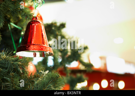 Close-up of red toy bell hanging on green spruce branch Stock Photo