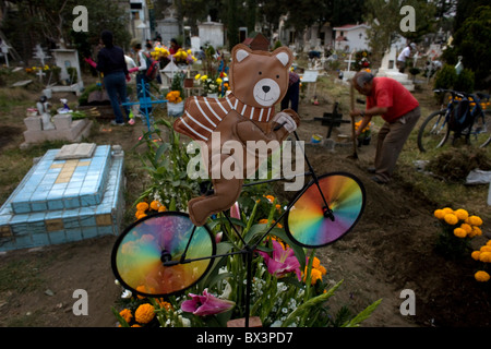 A toy bear on a bicycle decorates a tomb at the cemetery in San Gregorio Atlapulco, Xochimilco, Mexico City. Stock Photo