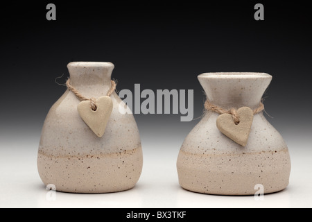 Two stone hearts on string wrapped around two ceramic pots Stock Photo