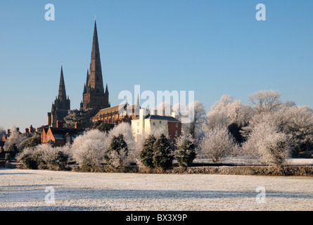 Lichfield Cathedral spires seen fro Stowe Fields under snow with hoar frost on trees and winter snow on ground under blue sky