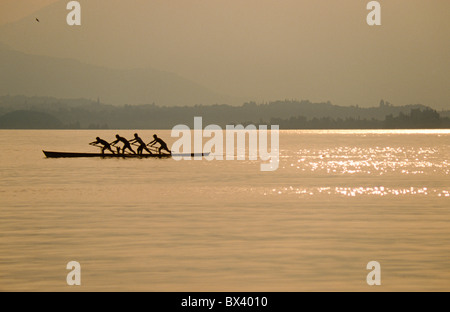 Four men rowing in the Venetian style known as 'Voga alla Veneta', on Lake Garda, Italy Stock Photo