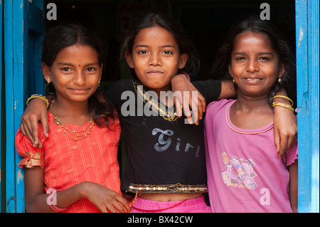 Smiling happy Indian village girls embracing in the doorway of their house.  Andhra Pradesh, India Stock Photo