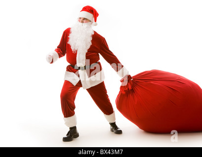 Portrait of happy Santa carrying heavy big red sack with presents Stock Photo