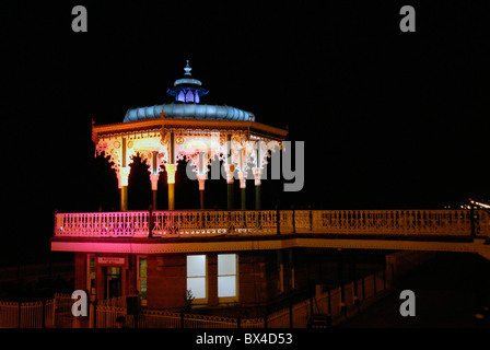 Brighton bandstand designed by Phillip Causton Lockwood in 1884 and restored in 2009, lit up at night on Brighton seafront. UK Stock Photo