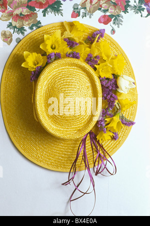 Still-Life of yellow straw hat decorated for Easter with yellow daffodils and blue violets Stock Photo