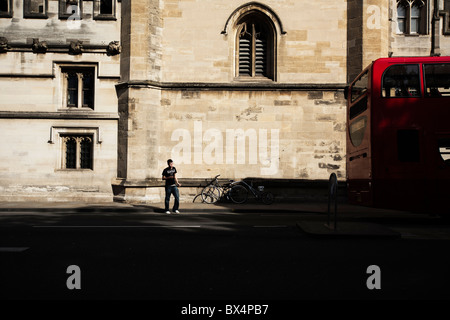 Oxford University student in front of Magdalen College with bus passing Stock Photo