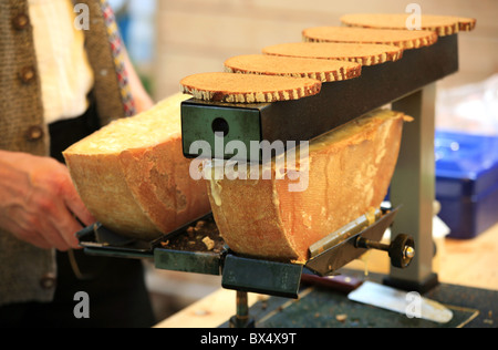 Man melting swiss raclette cheese to put it on toasted brown bread Stock Photo