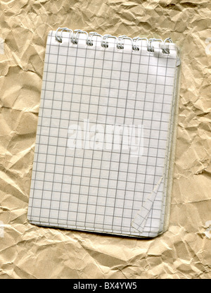 old notebook lying on a piece of crumpled yellow paper Stock Photo