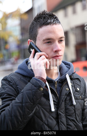 A young man using an Iphone on a U.K. street. Stock Photo