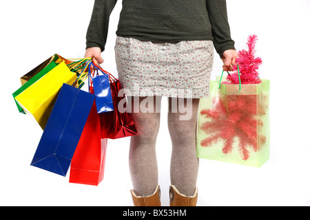 Young woman carrying gift boxes, cardboard boxes, of different sizes and colors, in different shopping bags. Stock Photo