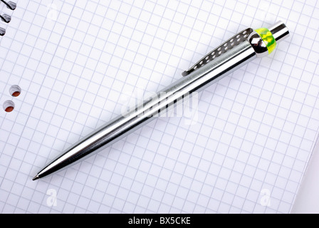 Ballpoint metallic pen laying on spiral notebook. Stock Photo