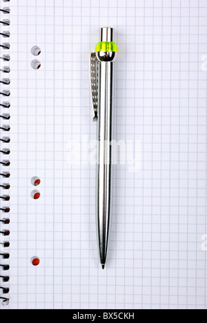 Ballpoint metallic pen laying on spiral notebook. Stock Photo