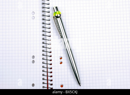 Ballpoint metallic pen laying on spiral notebook. Stock Photo