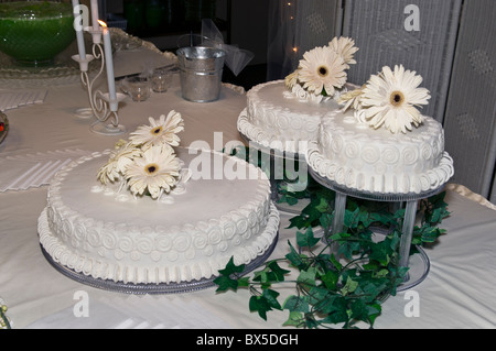 Three white wedding cakes with white floral decoration and greenery. USA. Stock Photo