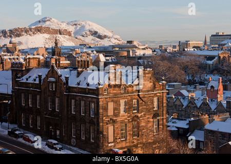 View across old Edinburgh from Castle Esplanade to Aurthurs Seat, blanketed in snow in the morning sun Stock Photo