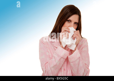 woman blowing her nose wearing pyjamas Stock Photo