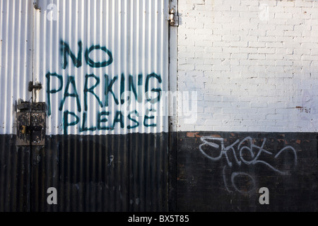 A hand-painted No Parking Please notice on a garage's gates under railway arches in south London. Stock Photo