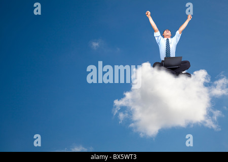 young businessman with computer sitting on the cloud Stock Photo