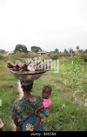 A mother carries a basket of fish with her daughter in Kakata, Liberia, West Africa. Stock Photo